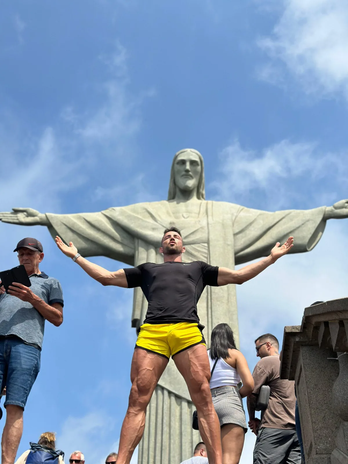 Maximo Garcia with arms open in front of Christ the Redeemer in Rio de Janeiro